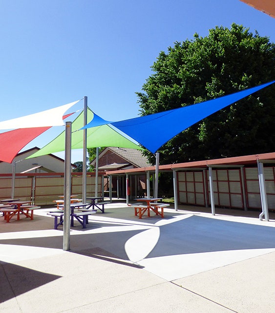 bright coloured sails coverings tables in chairs in courtyard at school