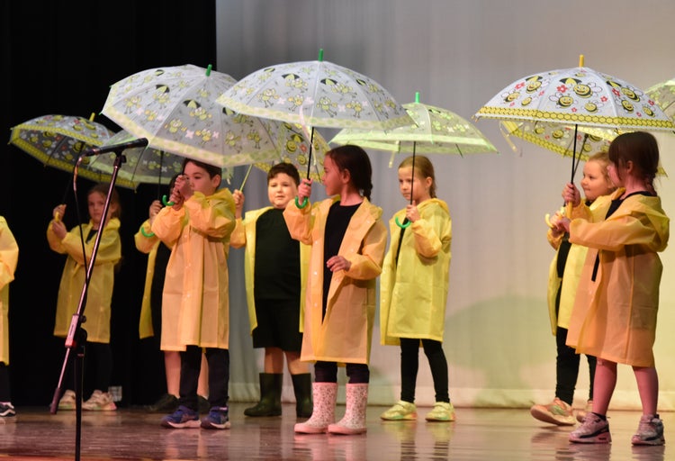 Kindergarten students perform dancing in the rain on stage